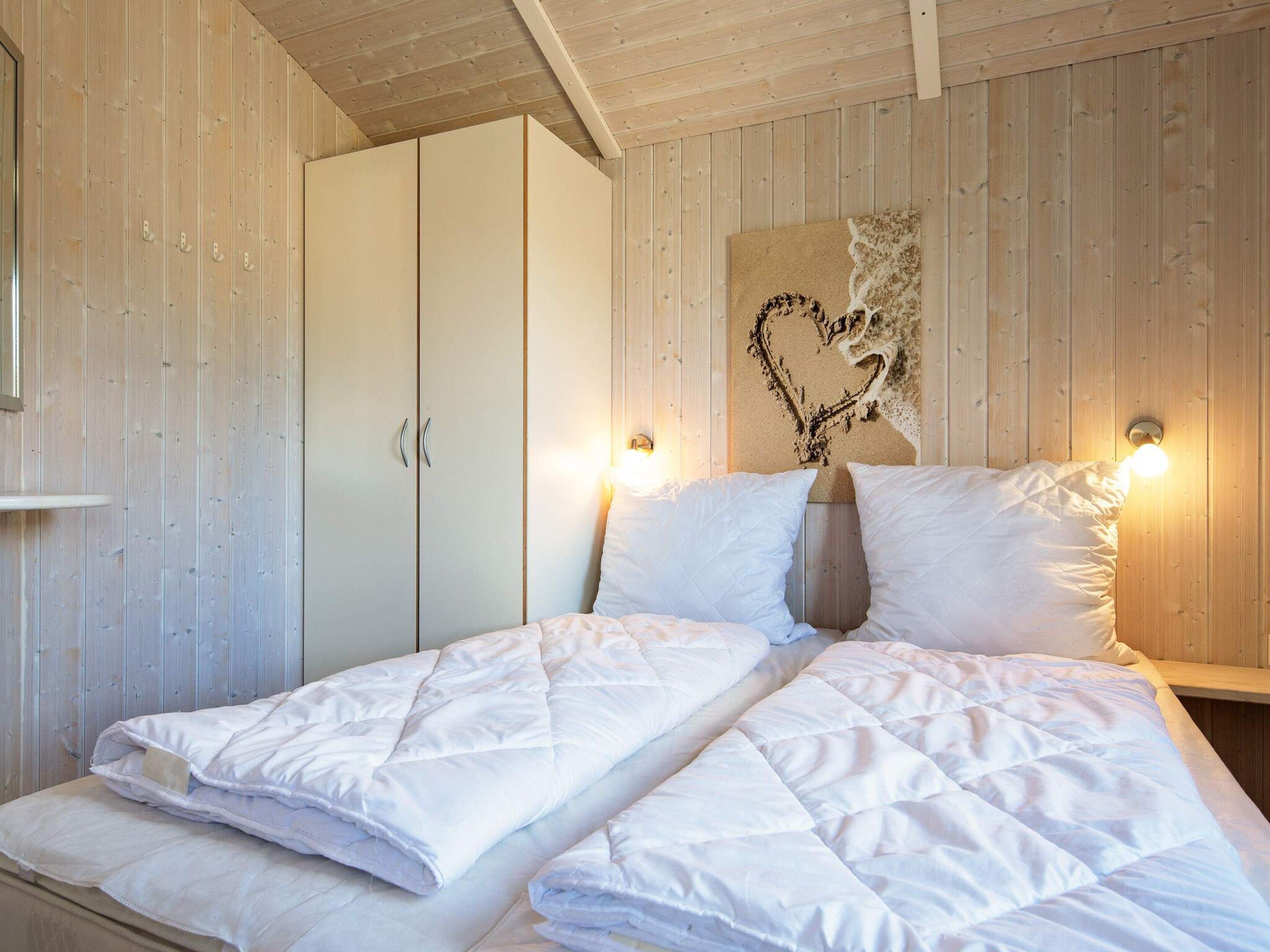 Ein Schlafzimmer mit einem Bett, einem Kleiderschrank und einer Wandleuchte.