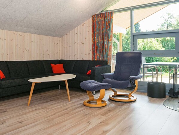 A modern room with a dark sofa, a round table, and a blue chair with wooden legs.