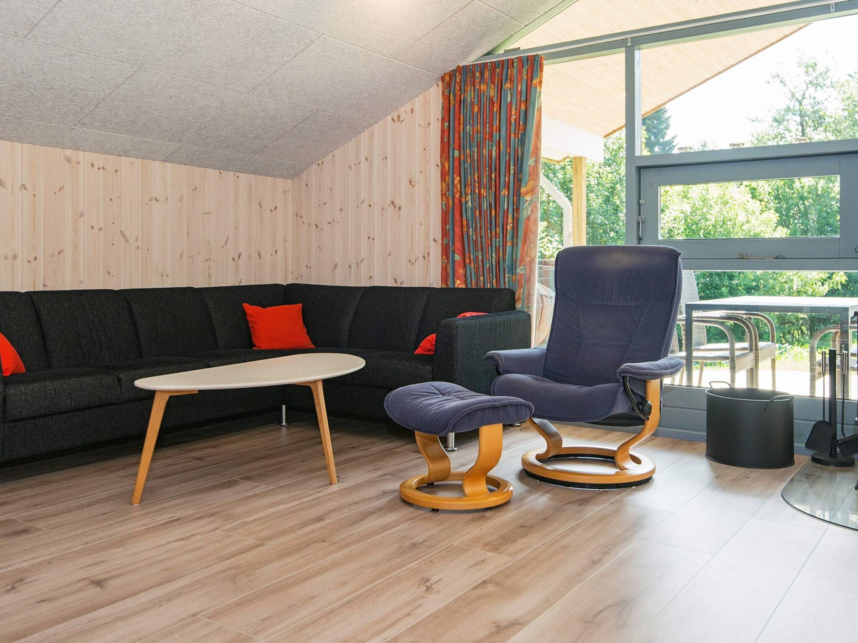 Una sala de estar moderna con un sofá negro, una mesa redonda y un sillón azul con patas de madera.