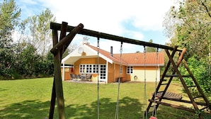 A wooden swing set in a backyard with a house in the background. - 8 Person Holiday Home in Oksbol (Oksbol)