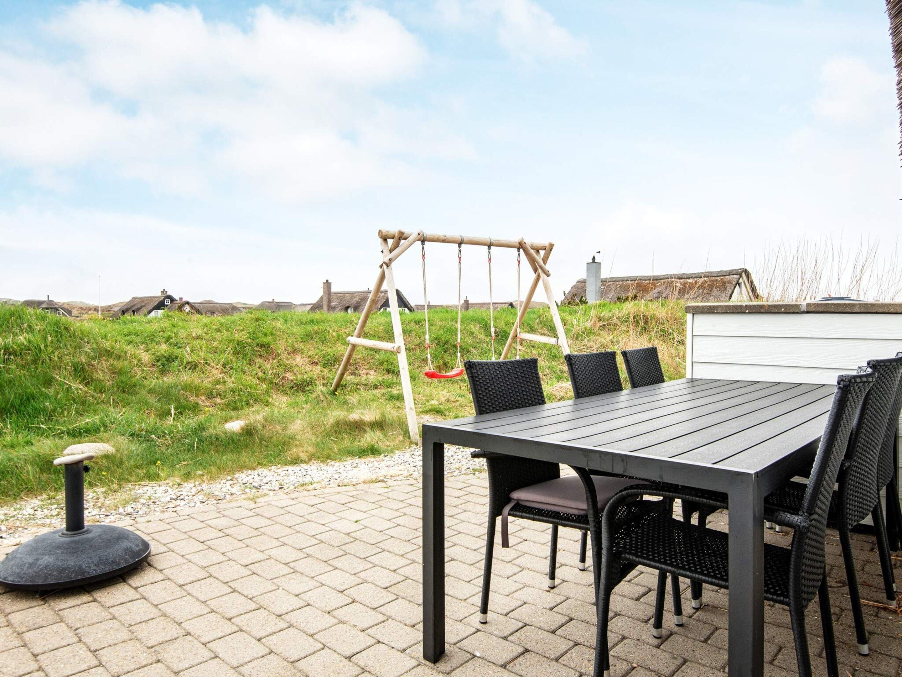 Eine Terrass mit Tisch und Stühlen, einer Schaukel und Blick ins Grüne.