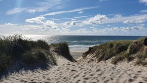 A sandy beach with dunes and a clear view of the ocean. - 4 Star Holiday Home in Ringkobing (Ringkobing)