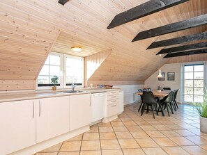 Una cocina con una isla grande, armarios blancos y un comedor con mesa y sillas.