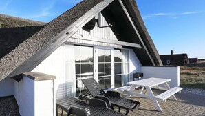 A modern building with a sloped roof, large glass windows, and outdoor seating. - 4 Star Holiday Home in Ringkobing (Ringkobing)