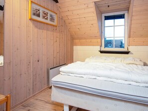 A bedroom with a wooden ceiling, a window, a bed with white bedding, and a framed picture on the wall. - 4 Star Holiday Home in Ringkobing (Ringkobing)