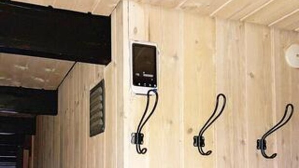 A wooden interior with a digital thermostat mounted on the wall, a vent, and three hooks. - 4 Star Holiday Home in Ringkobing (Ringkobing)