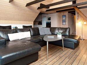 Ein modernes Wohnzimmer mit einer Ledersofa, einem runden Couchtisch und einer Holzbalkendecke.