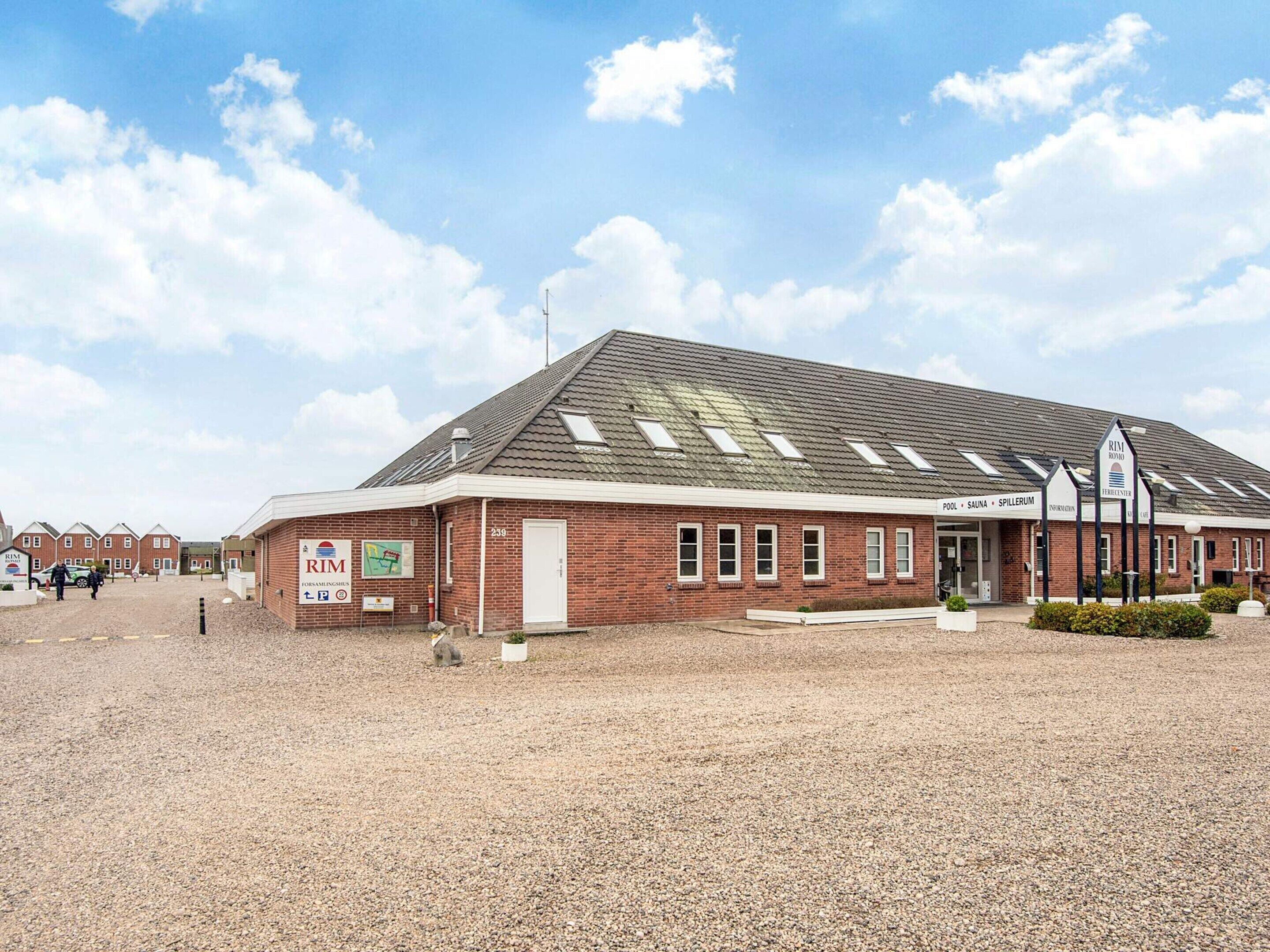 A building with a sloped roof, a sign for 'Rim Borno', and a sign indicating 'Pool, Sauna, Spillerum'.