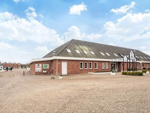 A building with a sloped roof, a sign for 'Rim Borno', and a sign indicating 'Pool, Sauna, Spillerum'.