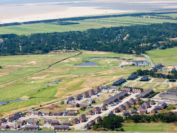 A residential area with houses, a golf course, and a body of water.