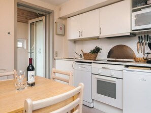 A kitchen with white cabinets, a microwave, a stove, and a dining table with chairs.