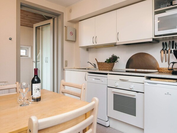 A kitchen with white cabinets, a microwave, a stove, and a dining table with chairs.