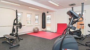 Un gimnasio con equipo de ejercicio, un saco de boxeo y una colchoneta roja.