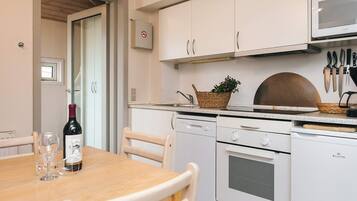 A kitchen with white cabinets, a microwave, a stove, and a dining table with chairs.