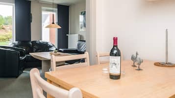 A dining area with a wooden table, chairs, a bottle of wine, and a decorative metal stand.