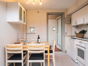 A compact kitchen with white cabinets, a dining table with chairs, and a small window.