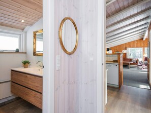 A modern bathroom with a wooden vanity, a large mirror, and a potted plant.