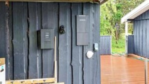 Un mur extérieur en bois, avec des boîtiers électriques, une porte et une petite fenêtre.