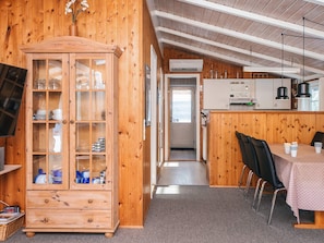 Un interior de madera con comedor, un aparador con puertas de cristal y una zona de cocina.