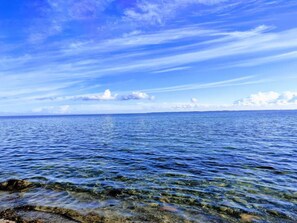 On aperçoit clairement une mer calme, avec une côte lointaine et un ciel partiellement nuageux.