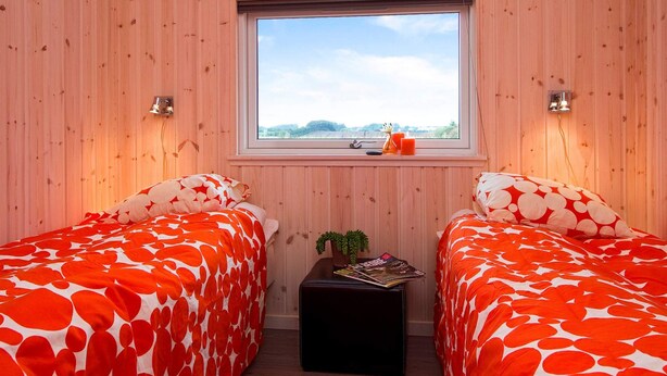 A room with two beds, a window, a small table with magazines, and a plant. - 5 Star Holiday Home in Sydals (Sydals)