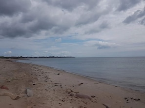 Uma praia com areal arenoso e águas calmas sob um céu nublado.