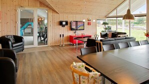 A modern interior with a wooden ceiling, a dining area with a large table, and a television mounted on the wall. - 5 Star Holiday Home in Sydals (Sydals)