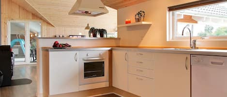 A modern kitchen with wooden cabinets, a built-in oven, and a window with a view.