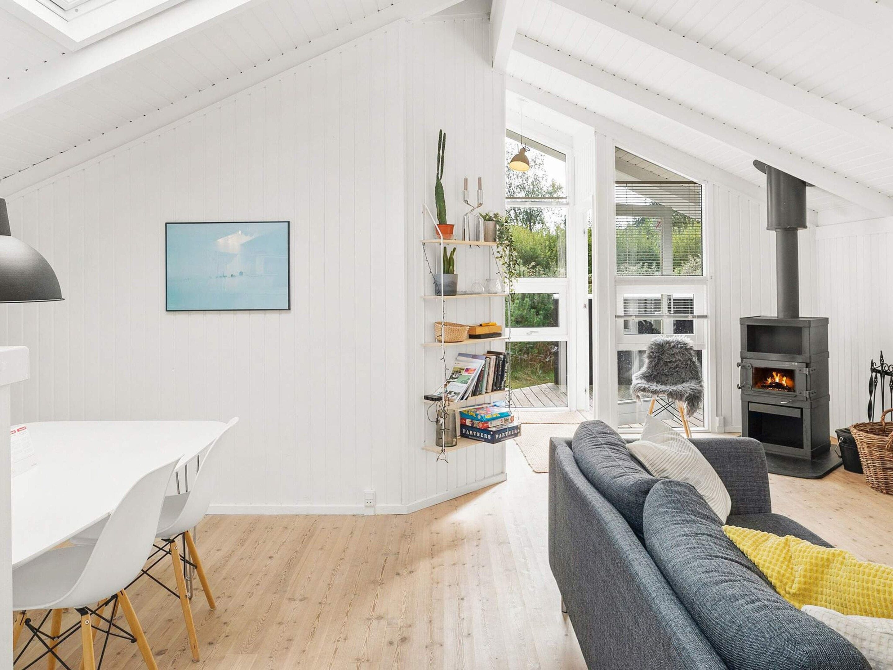 A modern living room with a high ceiling, a fireplace, and a view of the outdoors.