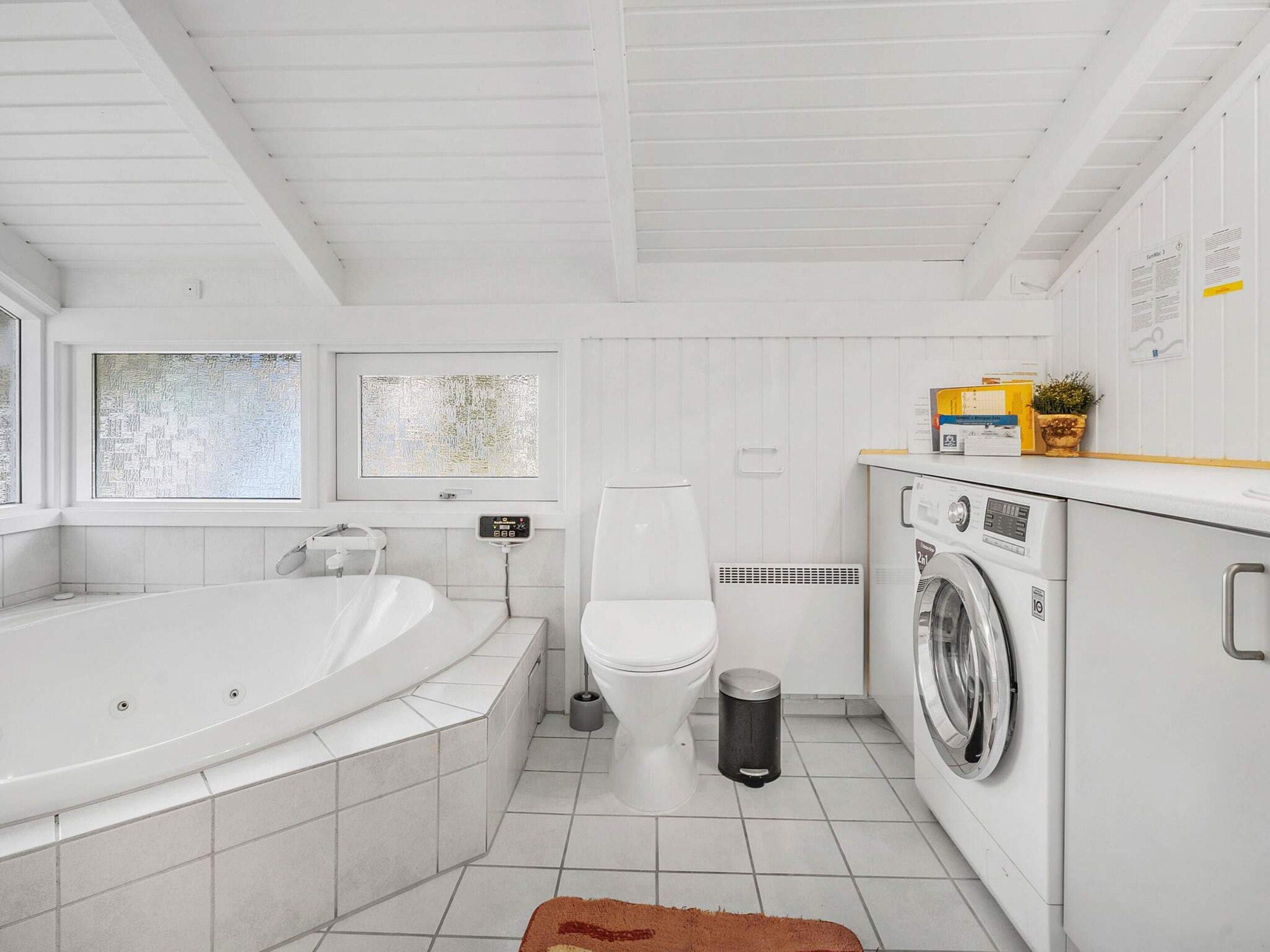 Ein modernes Badezimmer mit Badewanne, Toilette und Waschmaschine.