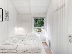 A room with two beds, a window with a view of greenery, and a white wall with a framed picture. - 4 Star Holiday Home in Albaek (Aalbaek)