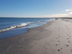 A beach with a pebbly shore, a clear sky, and footprints leading to the water. - 4 Star Holiday Home in Albaek (Aalbaek)