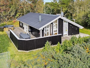 A modern two-story house with a deck, a hot tub, and a barbecue grill.