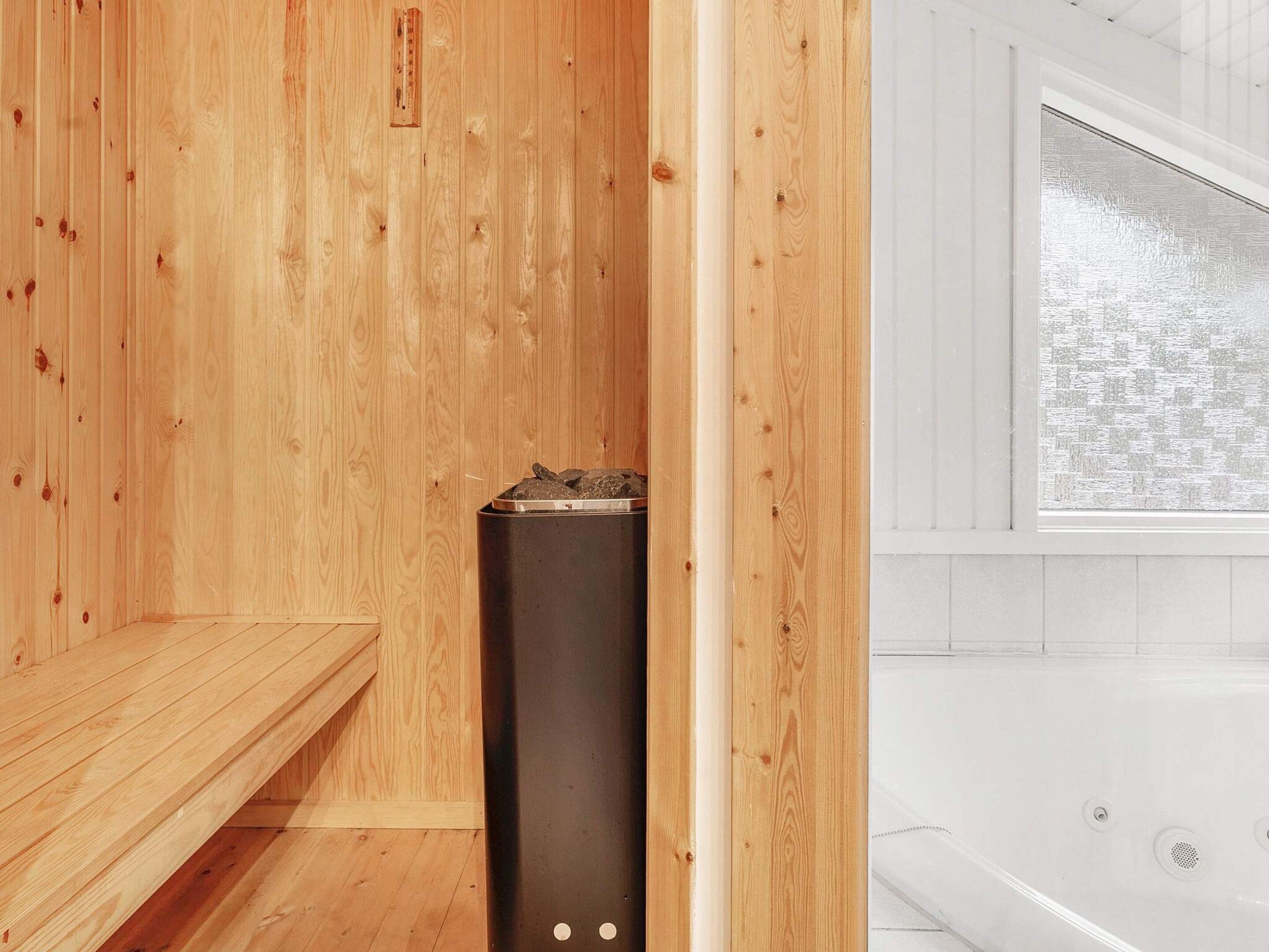 A sauna room with wooden walls, a bench, and a sauna heater.