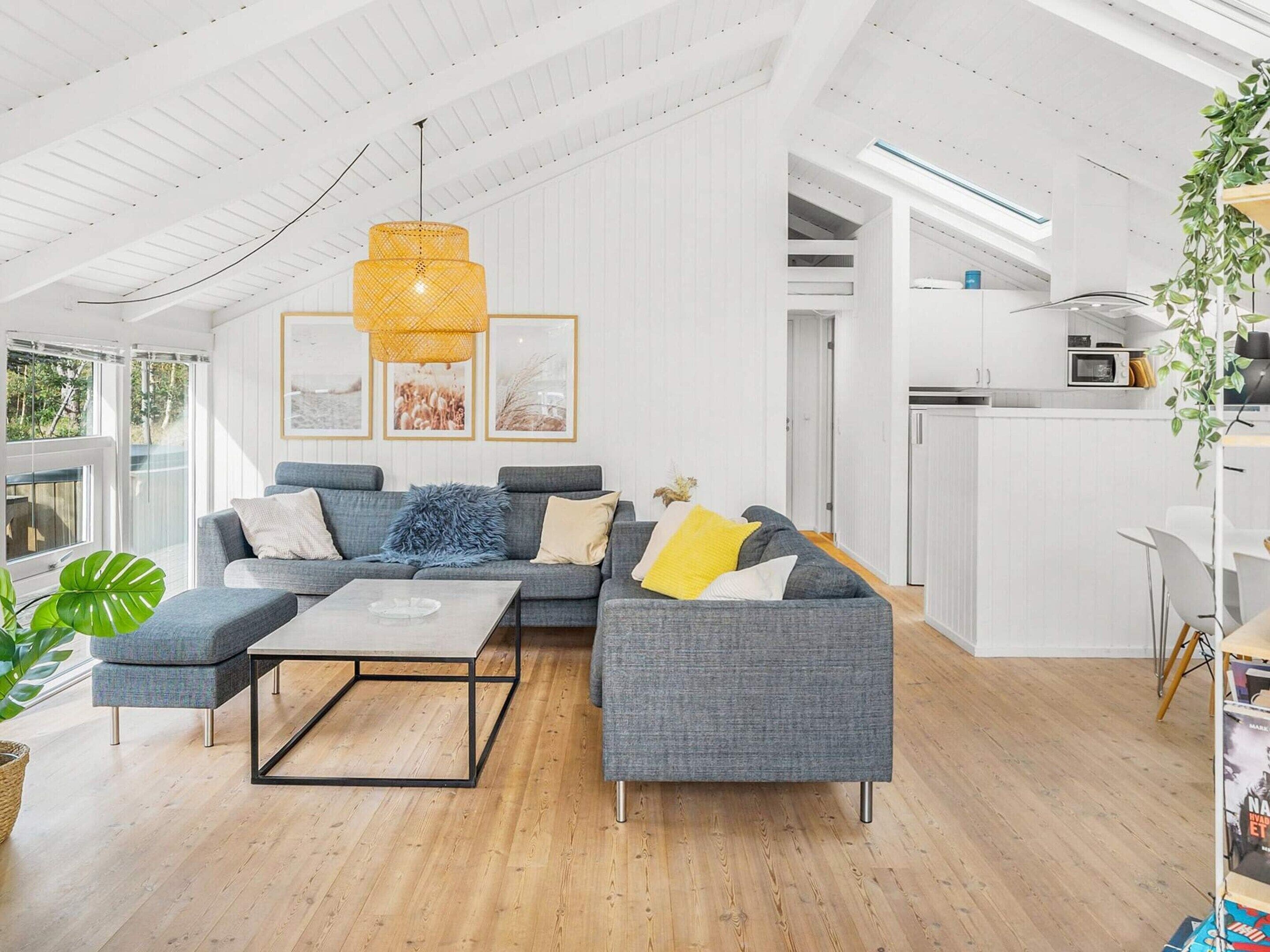 Een moderne woonkamer met een hoekbank, een salontafel en een hanglamp.
