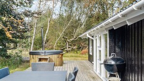 Terraza exterior con mesa y sillas, bañera de hidromasaje y parrilla.