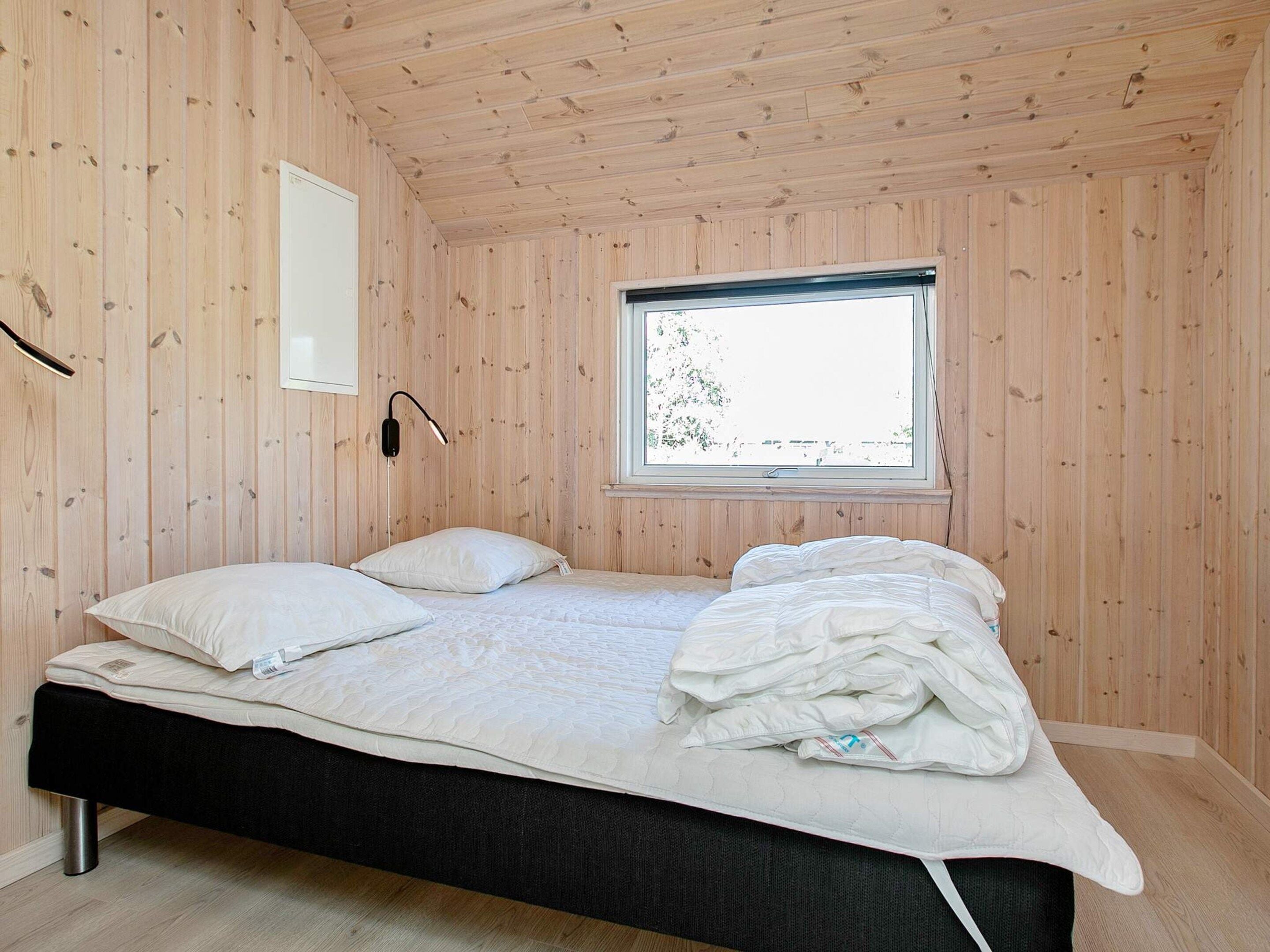 A room with a bed, a window, and wooden walls.