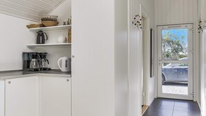 A modern kitchen with white cabinetry, a coffee maker, a kettle, and a shelf with decorative items.