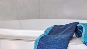 A bathtub with a towel draped over the side.