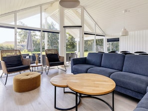 A modern outdoor seating area with wicker chairs, a blue sofa, and wooden tables.