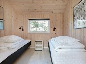 A room with two beds, a window, and a shelf. - 5 Star Holiday Home in Idestrup (Idestrup)