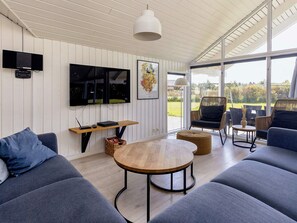A modern living room with a large sofa, a wooden coffee table, and a television mounted on the wall.