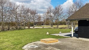 A grassy yard with a wooden bench, a paved area, and a building with a tiled roof.