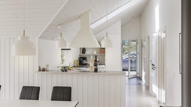 A modern kitchen with white cabinetry, a central island, pendant lighting, and a view to the outside.