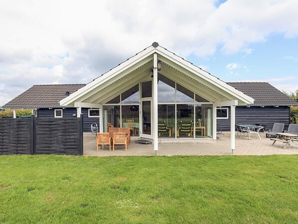 A house with a covered patio, a fenced yard, and a grassy lawn.