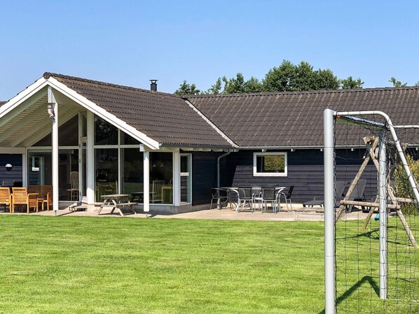A house with a covered patio, a dining area, and a fenced yard. - 4 Star Holiday Home in Idestrup (Idestrup)