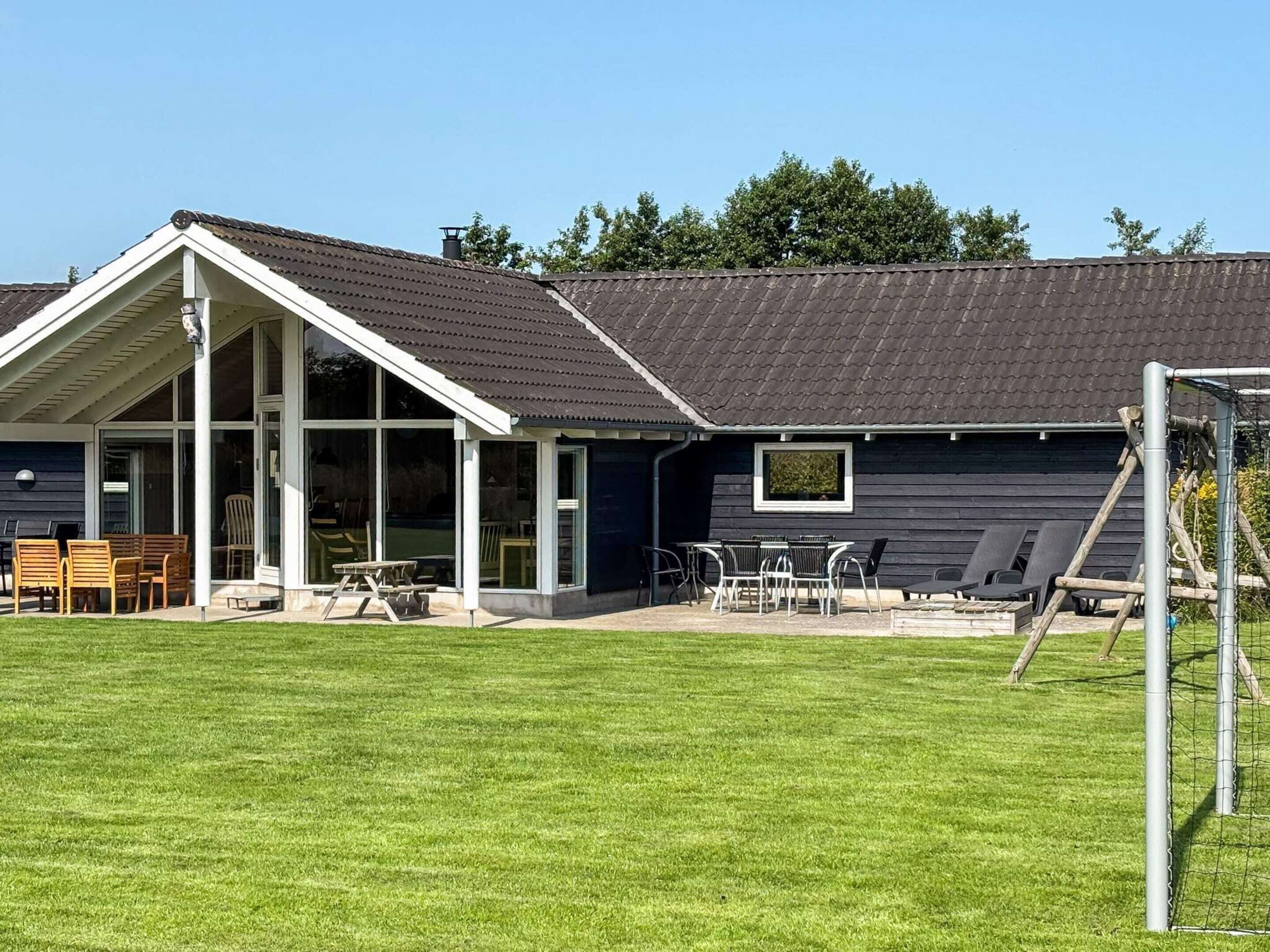 A modern building with a covered patio area, a lawn, and a soccer goal.