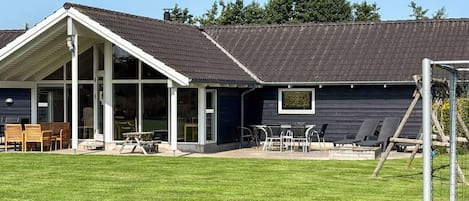 A modern building with a covered patio area, a lawn, and a soccer goal.