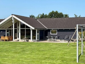 A modern building with a covered patio area, a lawn, and a soccer goal. - 4 Star Holiday Home in Idestrup (Idestrup)