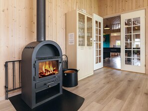 A wood-burning stove, a piano, and a dining area with glass doors. - 4 Star Holiday Home in Idestrup (Idestrup)